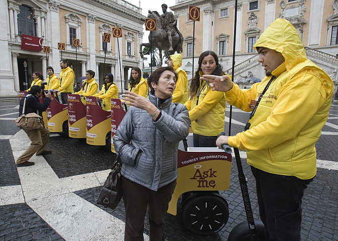 A tourist asks for directions from one of several mobile guides on Segway 'chariots' at city hall in Rome, Italy.