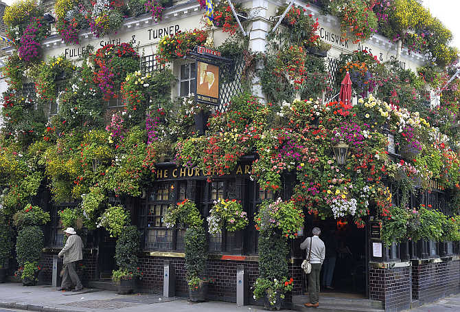 A customer stands outside The Churchill Arms pub in central London. The 18th century public house has twice won the 'London in Bloom' competition for its floral displays and hanging baskets which adorn the outside.