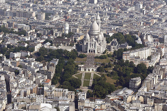 An aerial view shows the Sacre Coeur Basilica and rooftops of residential buildings on Montmartre in Paris, France.