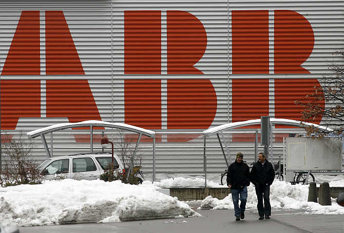 Two men walk in front of the logo of Swiss engineering group ABB in the town of Baden west of Zurich. ABB is another competitor of Havells.