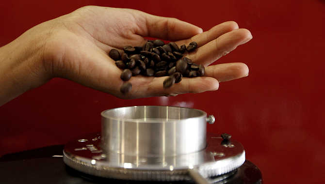 A waitress pours coffee beans into a grinder before she prepares an expresso at a coffee bar in Sao Paulo, Brazil. Havells manufactures domestic appliances among other products.