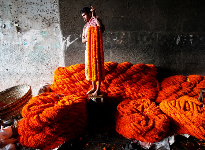 A vendor holds garlands of marigold flowers as he waits for customers at a wholesale flower market in Kolkata.