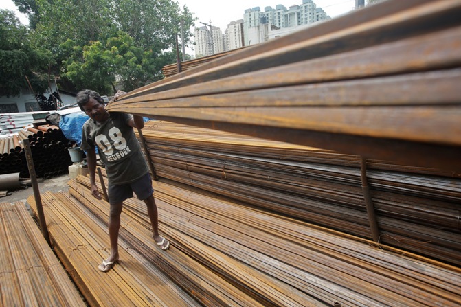 A worker loads iron rods in a truck at an iron and steel market in an industrial area in Mumbai.