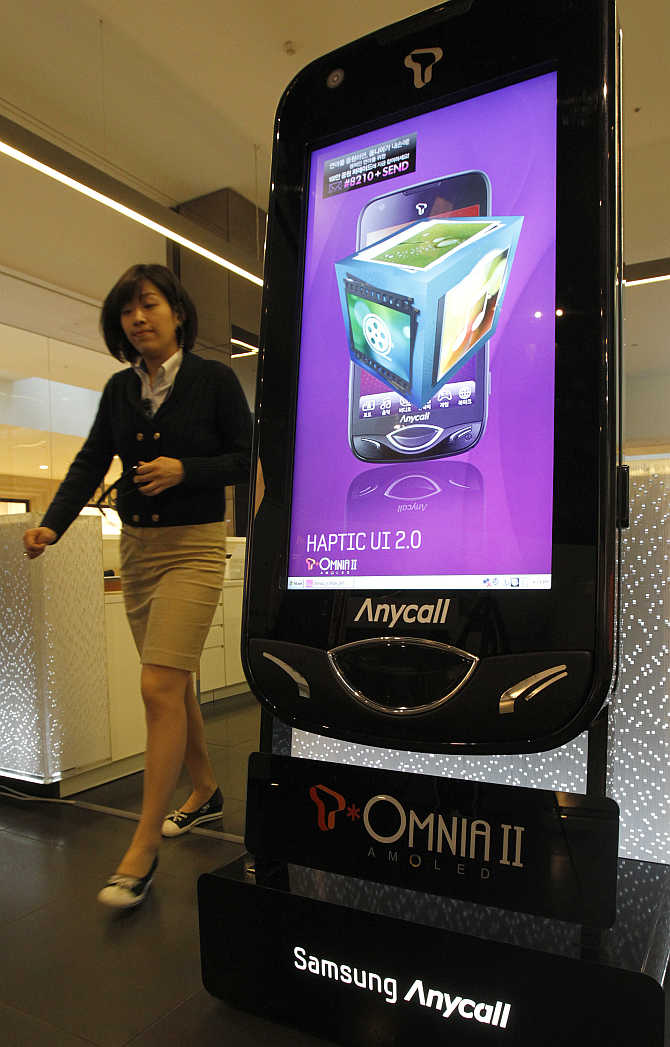An employee of Samsung Electronics walks past a large-scale replica of one of its mobile phones displayed for visitors at the company's headquarters in Seoul, South Korea.