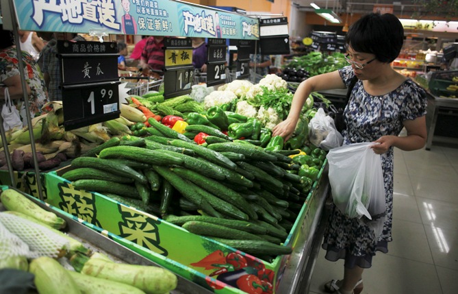 A customer selects green peppers at a supermarket in Beijing.