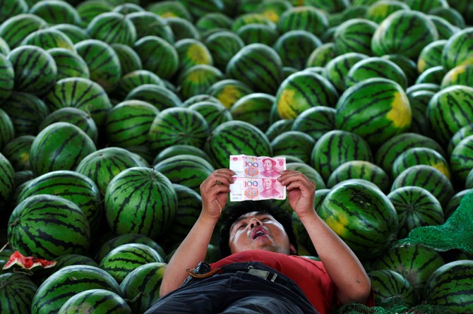 A watermelon vendor looks at yuan banknotes at a market in Changzhi, Shanxi province.