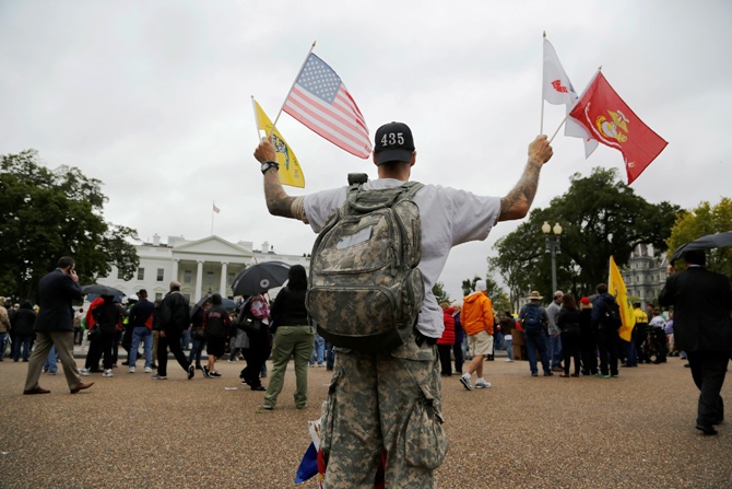 A man holds flags as protesters from the 'Million Vet March on the Memorials', rallying against the closure of the US National World War Two Memorial due to the current US government shutdown, demonstrate in front of the White House gates in Washington.