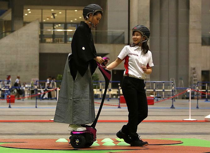 A staff member of Toyota Motor Corp (R) teaches a visitor, wearing Japanese traditional Kimono, how to ride its new personal mobility Winglet.