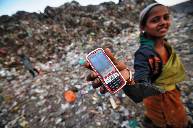 A ragpicker holds her mobile phone to show a picture she took at a dump yard in New Delhi.