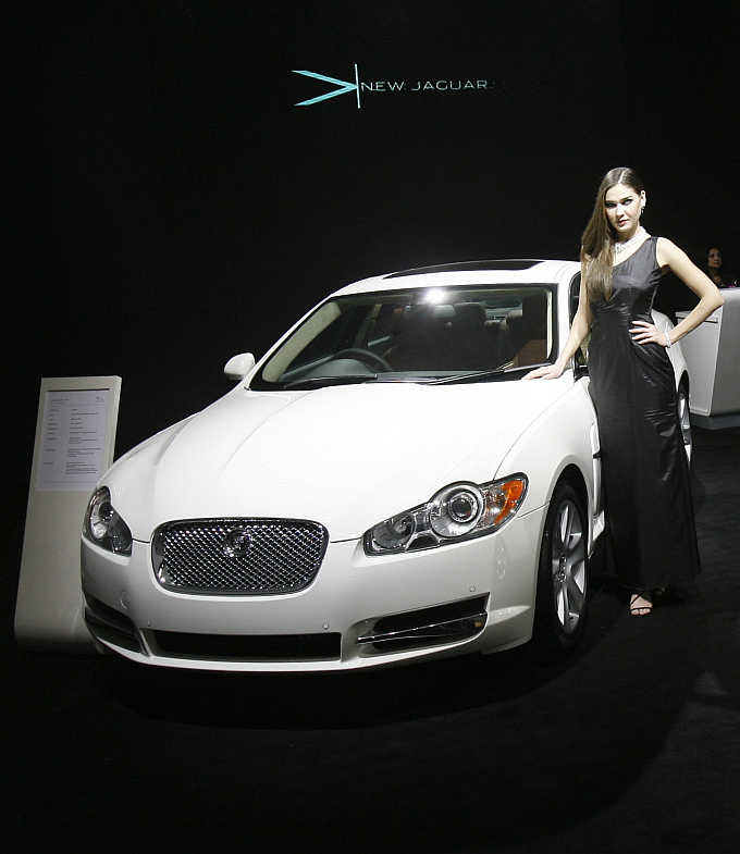 A model poses with a Jaguar XF at India's Auto Expo in New Delhi. Jaguar is a Tata brand.
