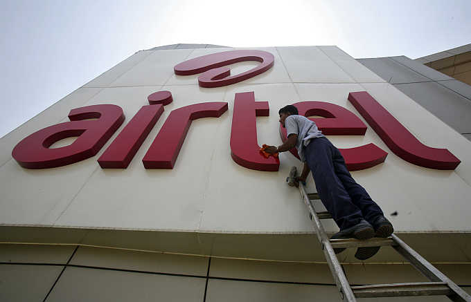 A worker cleans a logo of Bharti Airtel at its zonal office building in Chandigarh.