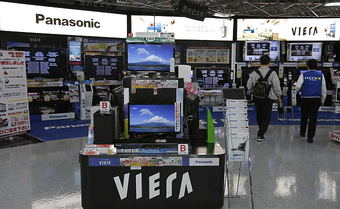 A man walks past Panasonic's Viera televisions displayed at an electronics store in Tokyo, Japan.