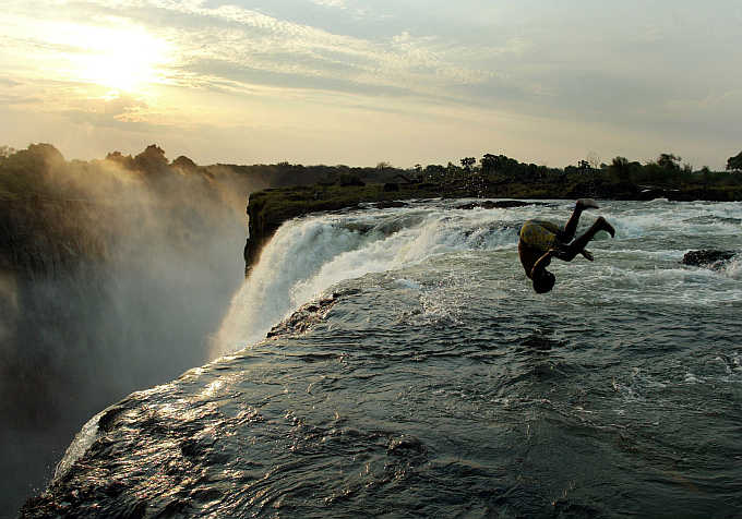 A man somersaults at the edge of the 110 metre high main falls of the Victoria Falls on the Zambezi River which forms the border between Zambia and Zimbabwe.