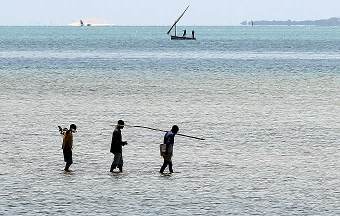 Fishermen walk to a boat on the Indian Ocean shore line in Vilanculo, Mozambique.