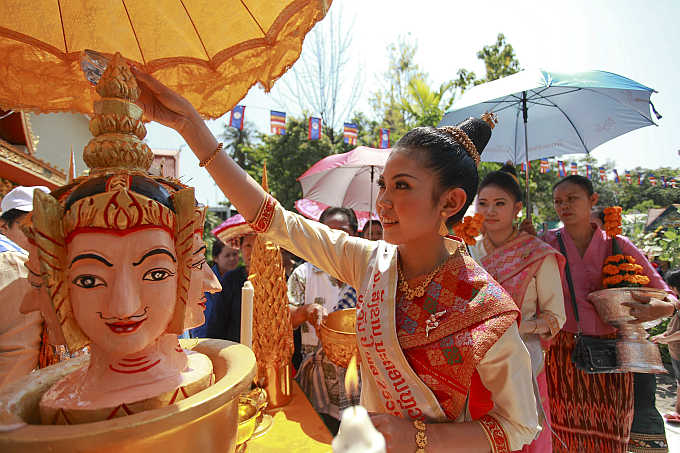 Nang Sangkhan, or Miss Lao New Year, pours water mixed with frangipanis and perfume over the head of a statue as she takes part in Lao New Year celebrations in capital Vientiane.