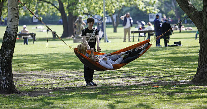 People relax in a hammock on a sunny day in Kampa park in central Prague, the Czech Republic.