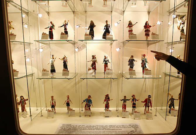 A curator points at dolls inside a display at the Doll Industry Museum in Taishan, Taipei County, Taiwan.