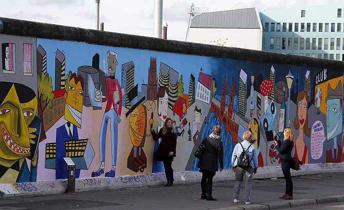 People take pictures of painted artwork of contemporary German Pop artist Jim Avignon at the open air 0.8-mile painted section of the Berlin Wall known as the 'East Side Gallery' in Berlin, Germany.