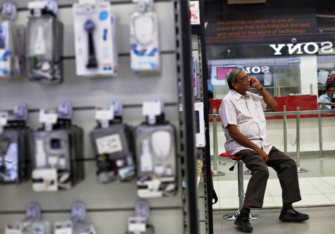A man speaks on his mobile phone as he sits outside an electronics store in New Delhi.
