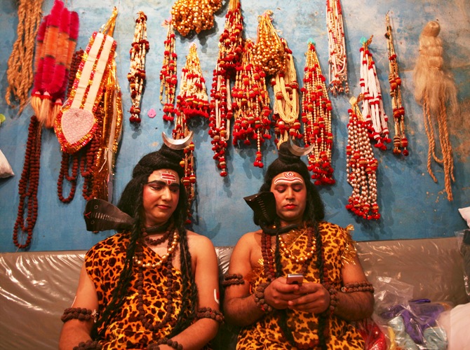 Artists dressed as the Hindu Lord Shiva read a message on a mobile phone as they prepare to participate in a religious procession ahead of the Mahashivratri festival in Jammu.