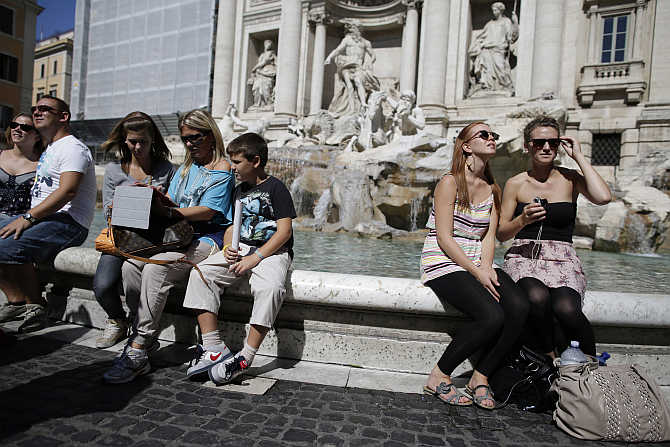 Tourists sit in front of Trevi Fountain in Rome, Italy.
