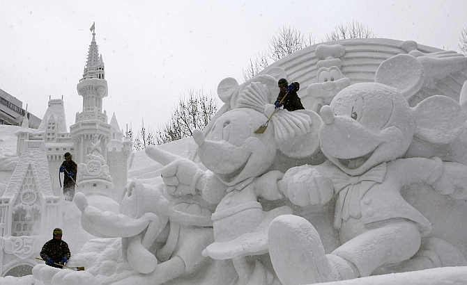 Soldiers clear snow on a sculpture celebrating the 25th anniversary of the Tokyo Disney Resort at a festival in Sapporo, northern Japan.