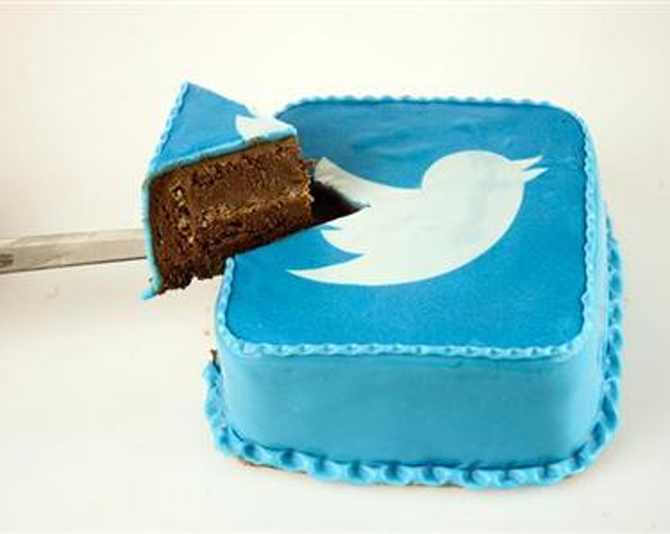 A person takes a slice of cake which is decorated in blue icing sugar with a Twitter logo at a bakery in Skopje.