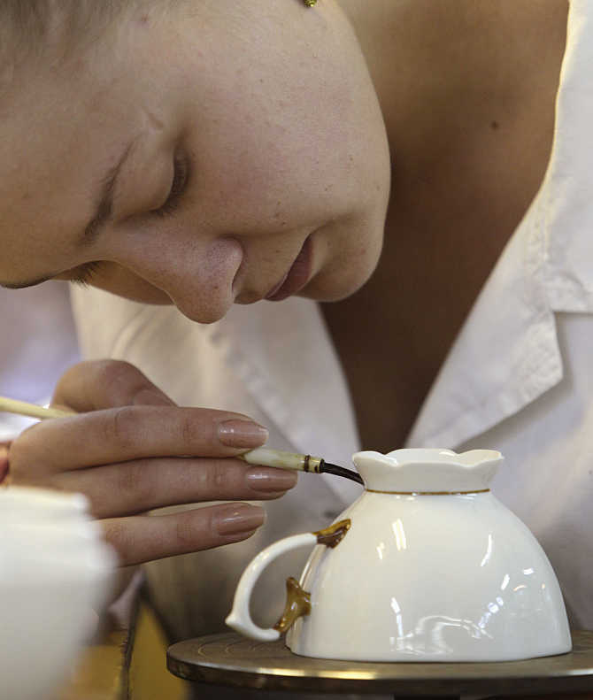 An employee paints a cup at a porcelain factory in the town of Dobrush, about 350km southeast of Minsk, Ukraine.