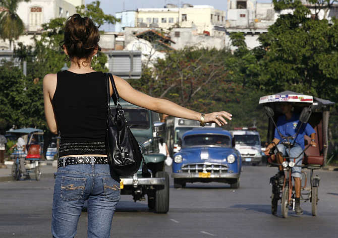 A woman hails a vintage car used as a taxi in Havana, Cuba.