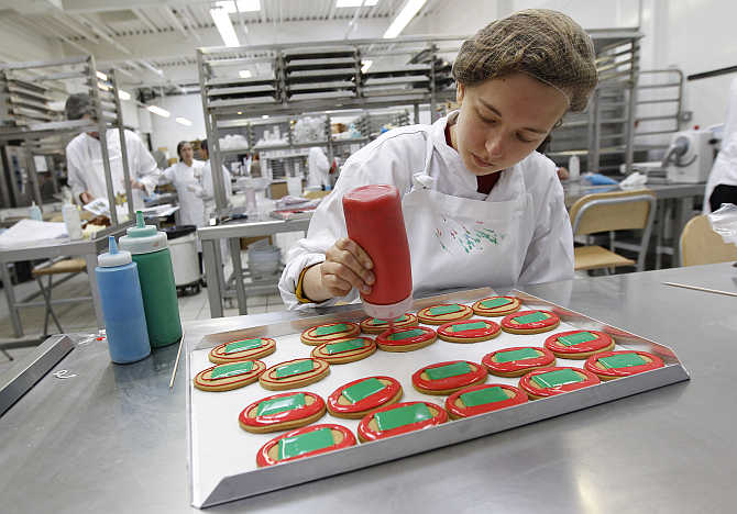 Lizzie Watts decorates biscuits depicting an athletics track and field at Biscuiteers in London, United Kingdom.