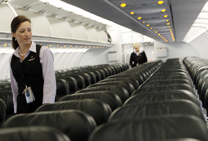 Frontier Airlines's flight attendant Cheryl Jacquot checks seats for safety cards before a trip to Washington, DC, at the Denver Airport, Colorado, United States.