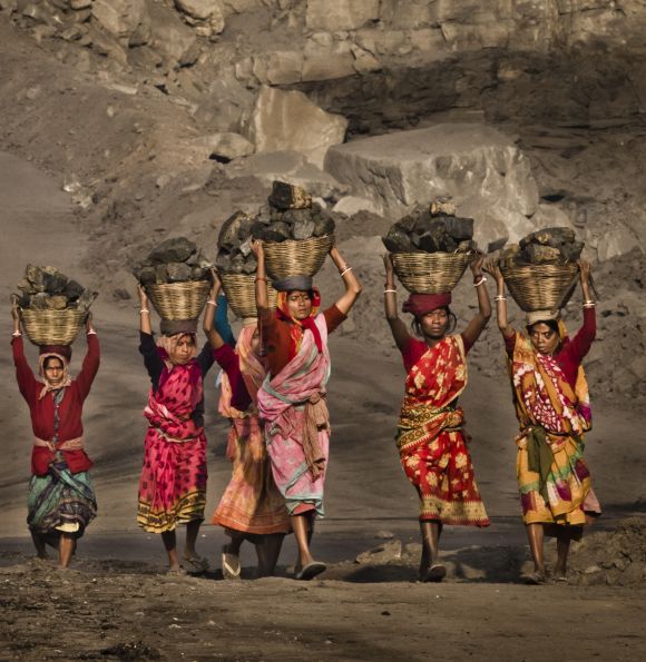 Local villagers carry coal after having scavenged it from an open-cast coal mine.