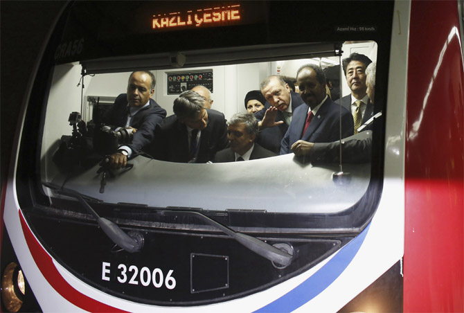 Japanese Prime Minister Shinzo Abe (R), Turkey's Prime Minister Tayyip Erdogan (3rd R) and President of Somalia Hassan Sheikh Mohamud (2nd R) stand around Turkey's President Abdullah Gul (seated) as he rides the ceremonial service of a train during the opening ceremony of Marmaray.