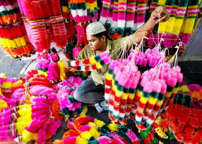 A vendor arranges artificial garlands for sale inside his shop ahead of Diwali in Ahmedabad.