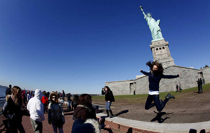 A visitor leaps beneath the Statue of Liberty at Liberty Island in New York, United States.