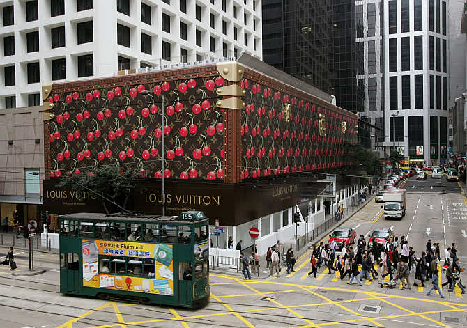 A tram passes a giant Louis Vuitton steamer trunk wrapping the exterior of a shopping mall at Hong Kong's Central Business District.