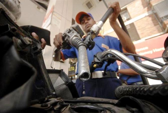 A worker holds a fuel nozzle at a petrol pump in Hyderabad.