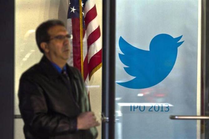 A man walks past a Twitter banner while leaving JP Morgan headquarters, before Twitter's IPO in New York October 25, 2013.