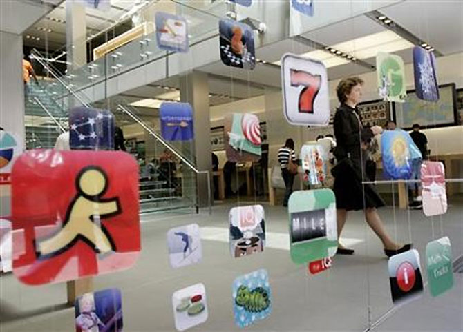 A woman walks past icons for Apple applications at the company's retail store.