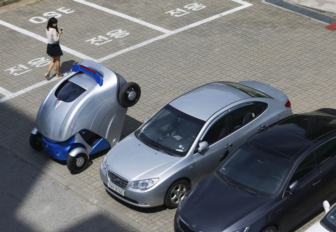 A woman walks past the folded Armadillo-T, a foldable electric vehicle, at the Korea Advanced Institute of Science and Technology (KAIST) in Daejeon, south of Seoul.
