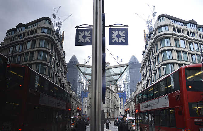 A logo from a Royal Bank of Scotland branch is reflected in a window in the City of London.