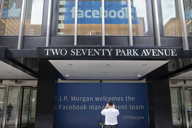 A man takes pictures of signs welcoming the IPO of Facebook outside the office of JP Morgan in New York City.