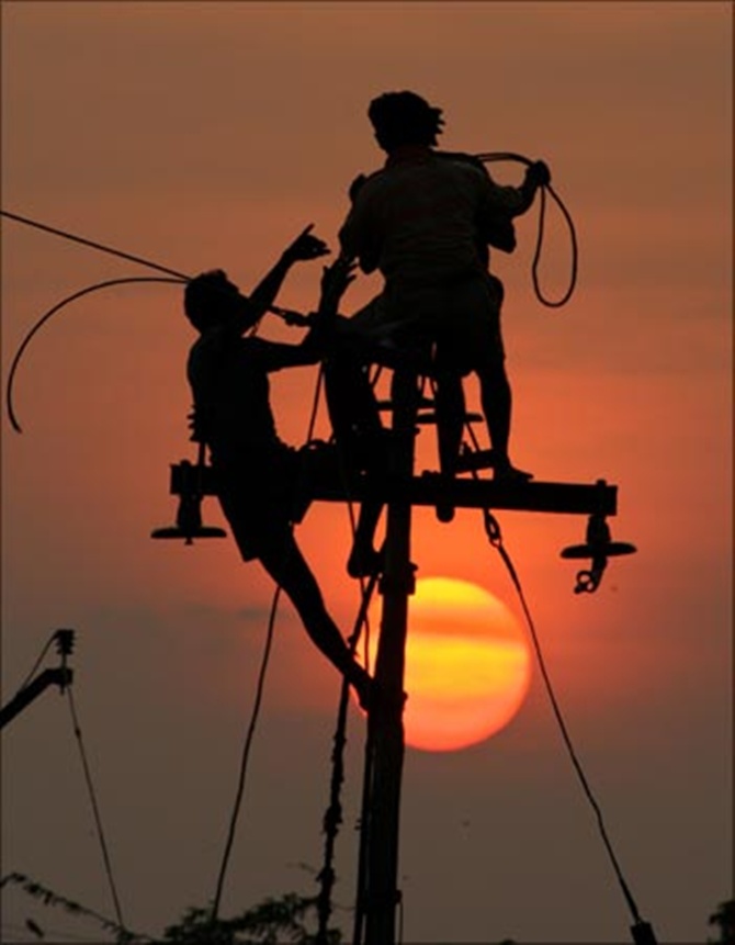 Workers install electric cables on a lamp post in Nagapattinam near Chennai.