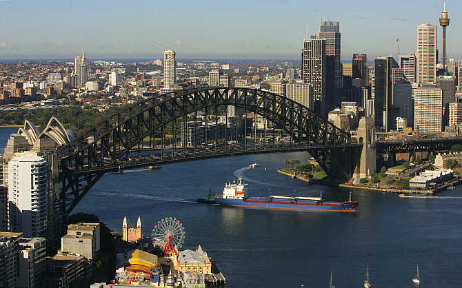 A cargo ship sails under the Sydney Harbour Bridge on its way in to port June, Australia.