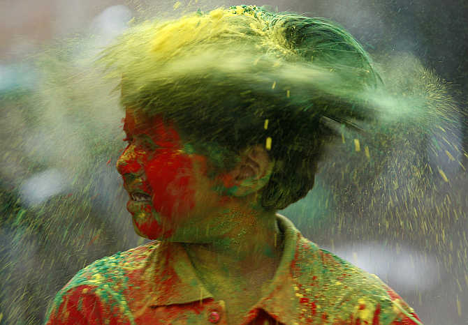 A boy shakes his head to remove coloured powder while celebrating Holi in Agartala.