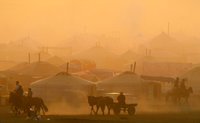 Mongolian horsemen pass a row of traditional tent houses known as ger near a horse race venue during the Naadam Festival at Khui Doloon Khudag village, some 35 kms (21 miles) outside the capital Ulan Bator.