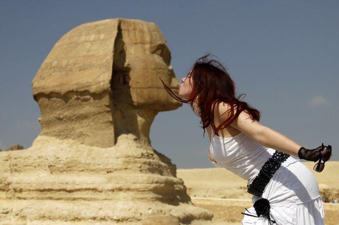 A tourist poses for a picture with the Sphinx at the Pyramids of Giza in Cairo.