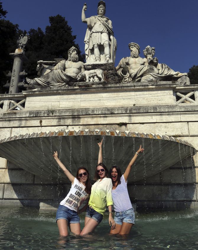 Girls pose for a picture in a fountain on a hot summer's day in Rome.