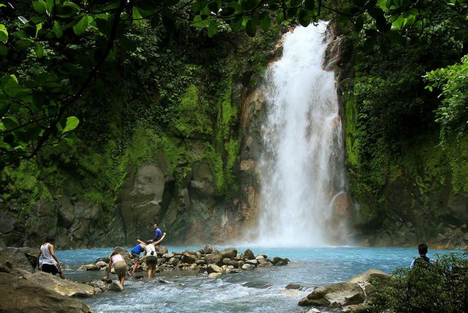 People swim in the Celeste river waterfall at Tenorio Volcano National Park in Upala.