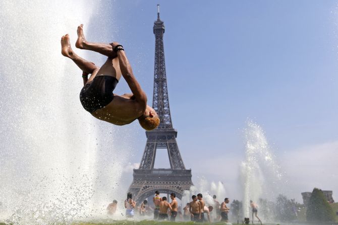 A man jumps in a fountain of the Trocadero Square in front of the Eiffel Tower.